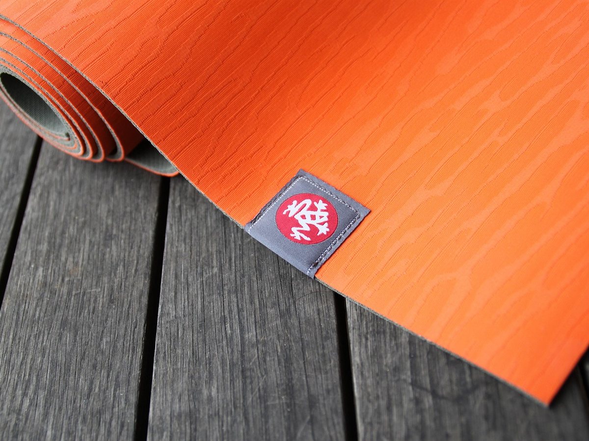 Tapis de yoga déroulé sur un parquet en bois